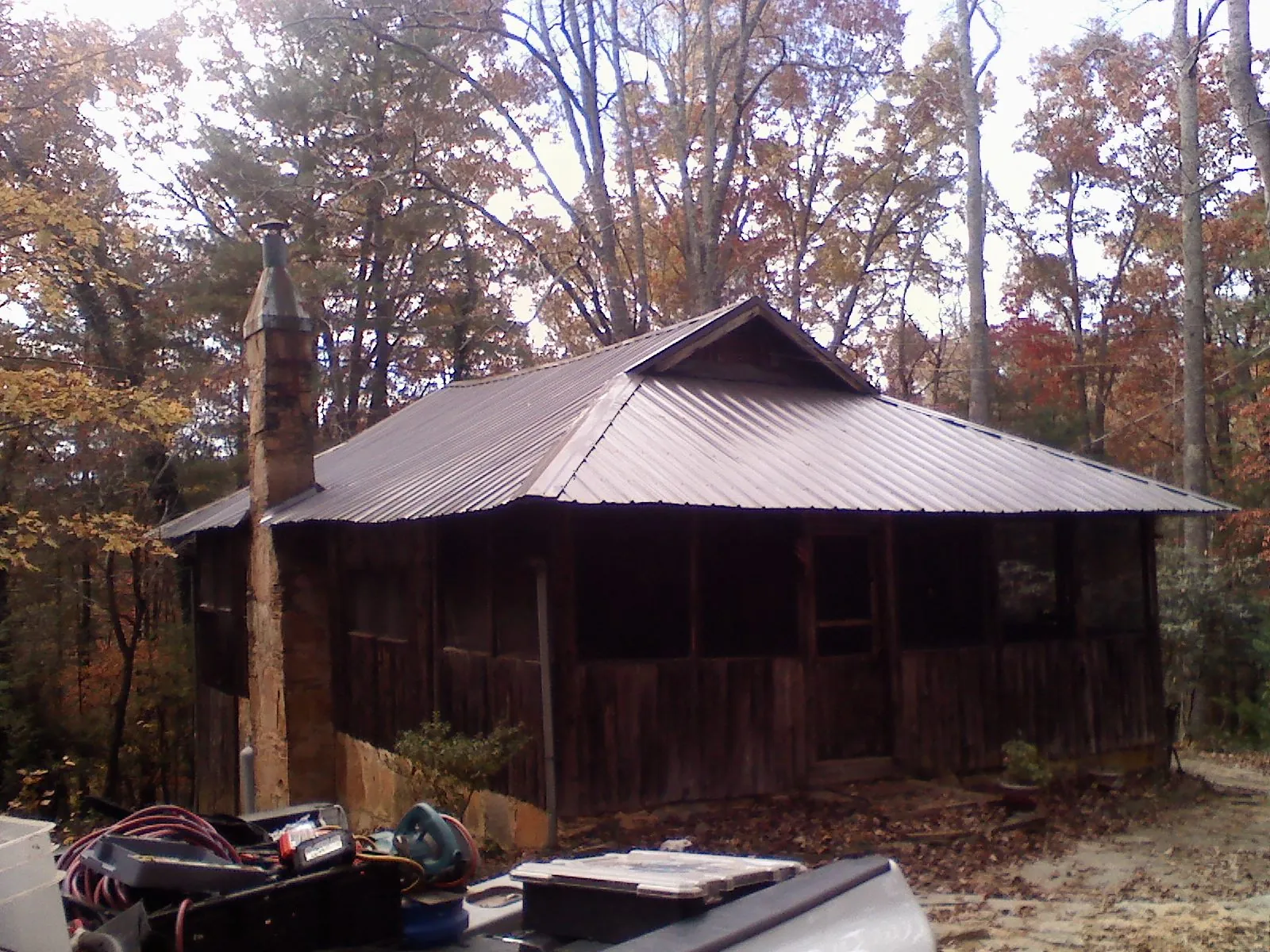 Brown metal hip roof on an old cabin with a stone chimney in Spotsylvania