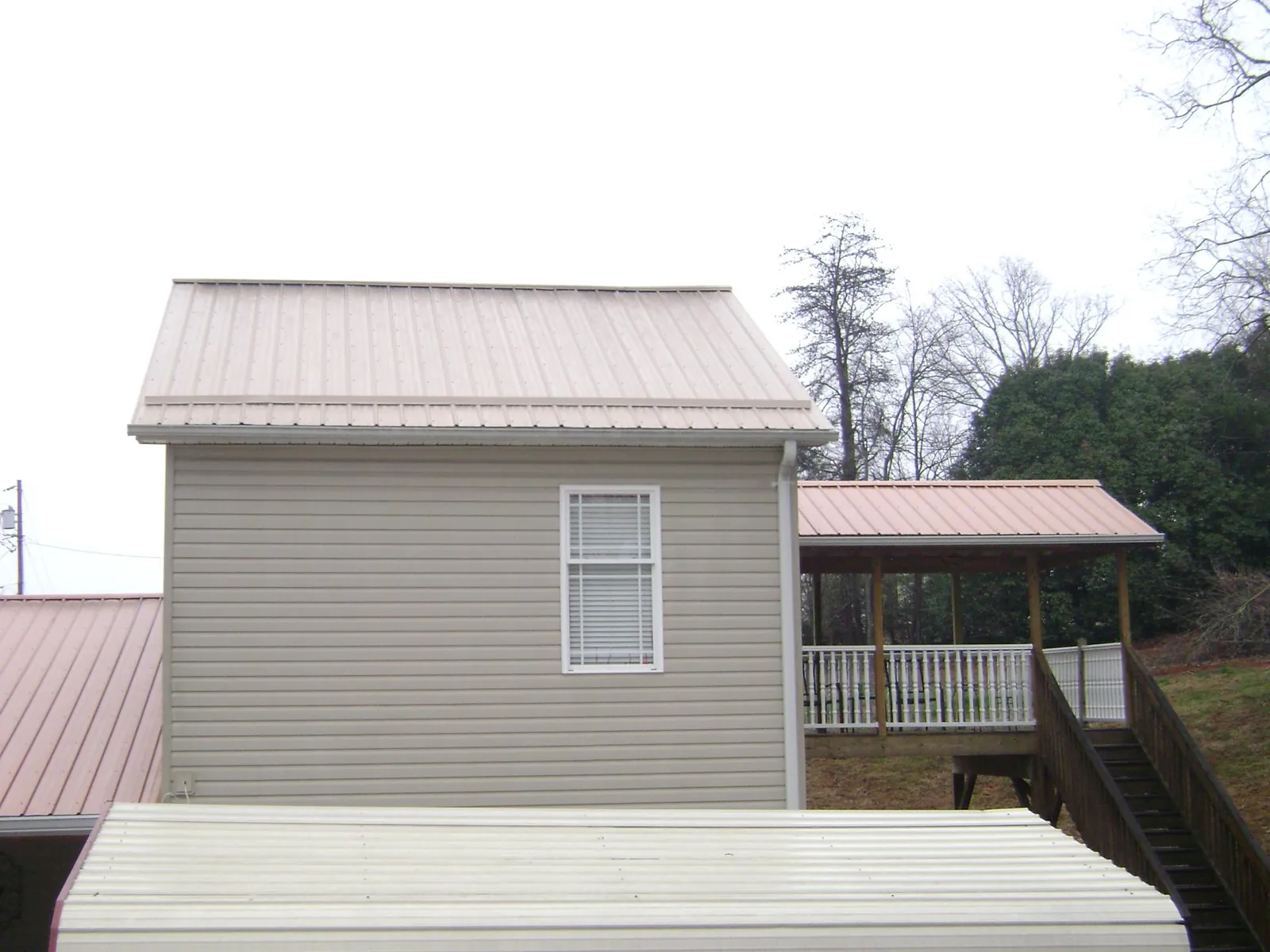 Tan metal roofs on a two story addition and attached porch, from a Roof Replacement job in Spotsylvania