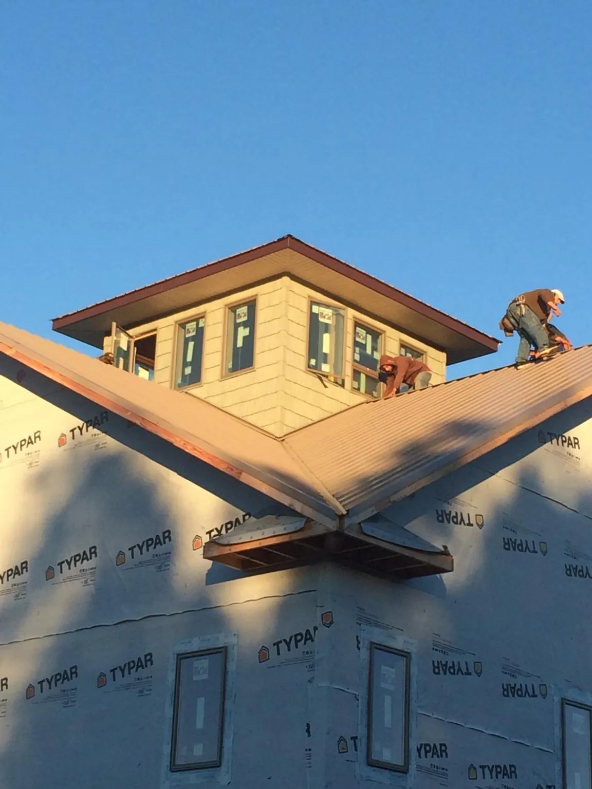 Roofers working around a rooftop cupola on a new metal roof at sunset — Roof Waterproofing in Spotsylvania by Roofing Brothers